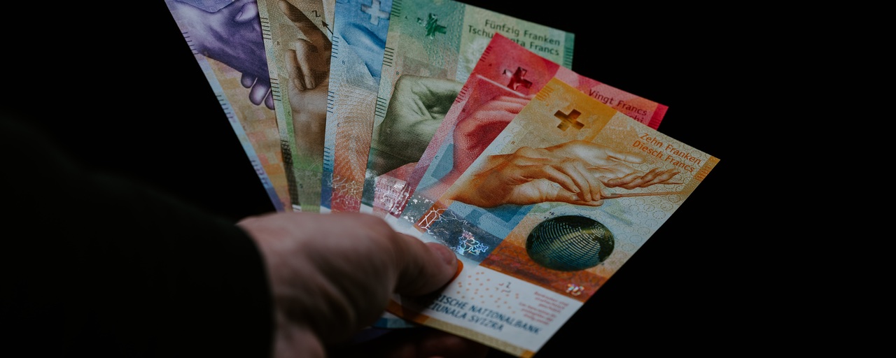 Hand mit Fächer aller aktuellen Banknoten auf schwarzem Hintergrund