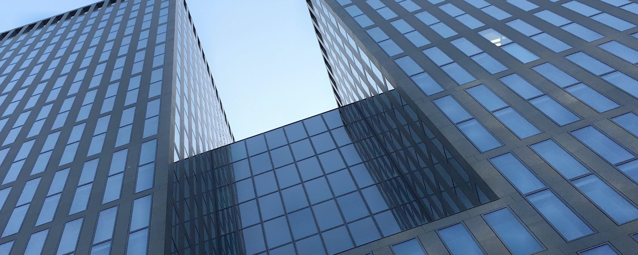Symbolbild: Gebäude mit Glasfassade in Richtung Himmel aufgenommen